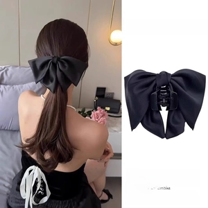 Detail of a large black satin bow hair claw clip shown on a model for French style hair styling