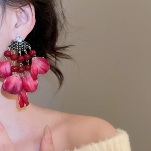 Detailed view of elegant red fabric petal tassel earrings with crystal studs on a model