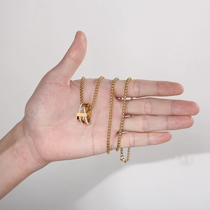 Detail of hand-held gold interlocking triple ring pendant necklace with sparkling zircons