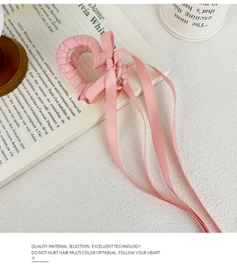 Dettaglio della molletta a cuore in nastro di raso rosa con eleganti nastri fluenti