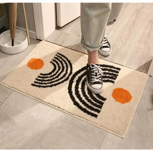 Close-up of plush beige bathroom mat with black stripes and orange circular pattern