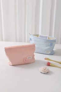 Close-up of checkered makeup bag with zipper closure and floral side charm decoration