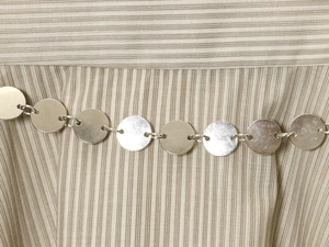 Détail du tissu à rayures avec une chaîne décorative de disques métalliques argentés