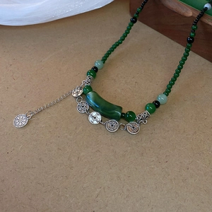 Détail d'un collier de perles vintage avec perles en résine verte et pièces chinoises