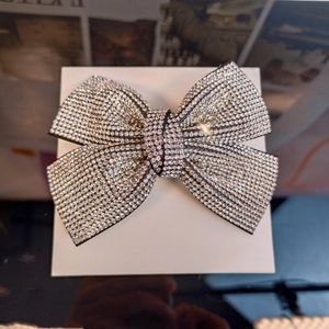 Detailed view of a silver rhinestone bow clip with sparkling crystals on black fabric base