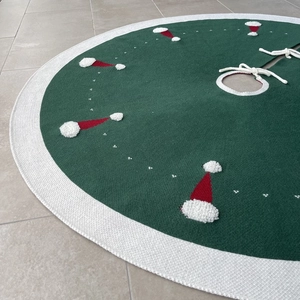 Détails du tricot de ce tapis de sapin vert orné de motifs de bonnets de Noël