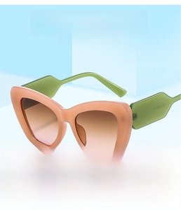 Detail of pink cat-eye sunglasses with contrasting green temples and gradient lenses