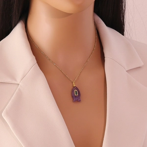 Detailansicht einer Goldkette mit lila Fisch-Anhänger am Hals eines weiblichen Models