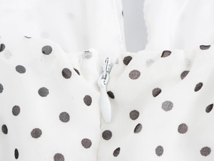 Vue macro détaillée de la fermeture éclair blanche invisible sur la robe à pois noirs