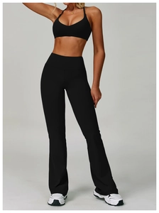 Detail of high-waist flared yoga pants and strappy sports bra in black performance fabric