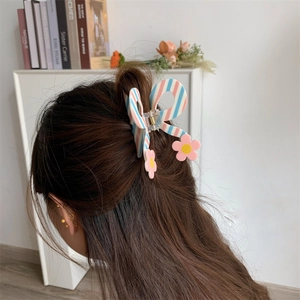 Detail showing a blue and pink striped butterfly hair claw clip with daisy flower accents