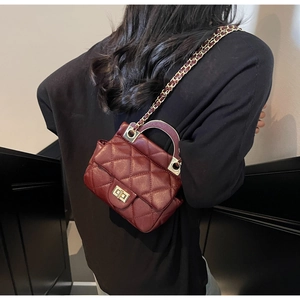 Quilted burgundy chain crossbody bag with golden clasp shown on a model