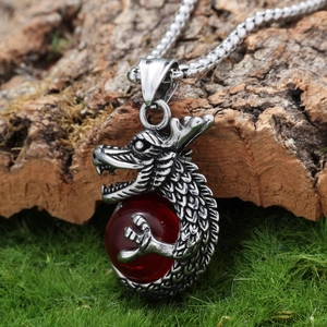 Retro stainless steel dragon pendant with red bead on natural tree bark background