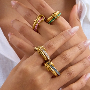Close-up of four interlocking gold-plated rings with colorful zircon stone settings