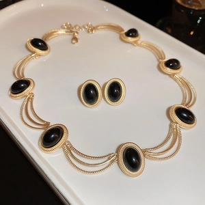 Detail view of vintage gold necklace and oval black gemstone earrings on a tray