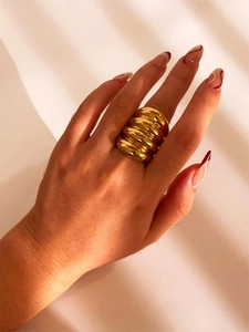 Detailed view of a gold croissant-style textured dome ring on a finger with a soft background