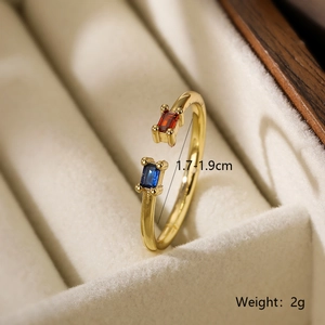 Detail of adjustable gold ring with blue and orange gemstones in velvet box