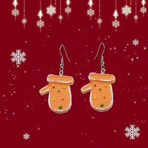 Détail de boucles d'oreilles gant de pain d'épices orange sur fond rouge à flocons de neige
