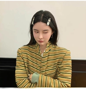 Detail of a chic striped knit cardigan with high collar and metallic button fastener