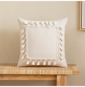 Detail of bohemian beige tassel cushion cover with textured cotton fabric on a rattan chair