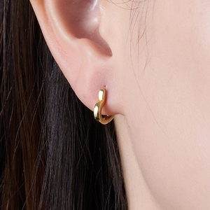 Close-up of a minimalist gold heart-shaped hoop earring worn on a model ear
