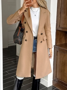 Close-up of camel double-breasted long coat paired with white turtleneck and denim skirt