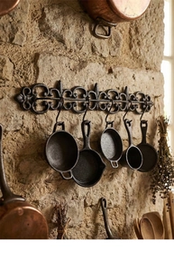 Détail de la décoration murale de cuisine en fonte vintage avec tige gaufrée et cinq mini poêles