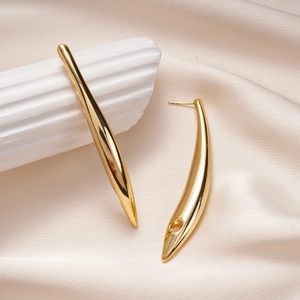 Detail of 18K gold plated bar earrings on elegant silk fabric with plaster decoration