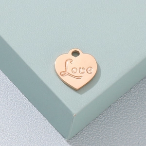 Gros plan du pendentif cœur en acier inoxydable gravé Love sur une boîte verte