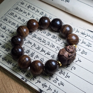 Gros plan de perles de prière en bois d'agar avec breloque Bouddha sur livre