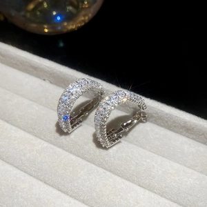 Macro detail of silver triangular hoop earrings with pavé zircons on grey velvet tray