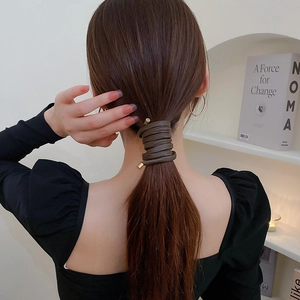 Detail of dark brown leather hair wrap with gold metal tips for ponytail styling