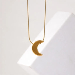 Elegant gold crescent moon pendant on a sleek snake chain against a minimalist background