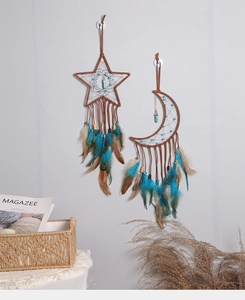 Detailed view of moon and star dreamcatchers with turquoise feathers hanging on a wall