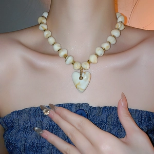 Close-up of heart acrylic necklace with cream marble beads and gold metal spacers