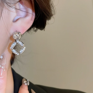 Detail view of 18K gold plated silver needle pearl earrings on model with soft lighting