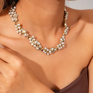 Détail d'un collier vintage en or avec perles et cristaux scintillants sur mannequin