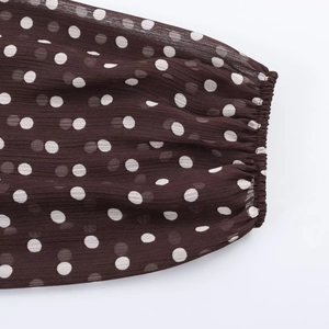 Detailed close-up of brown polka dot chiffon blouse with elastic cuff and textured fabric