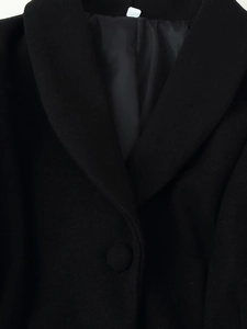 Close-up of the shawl lapel and fabric texture on a long black wool coat for women