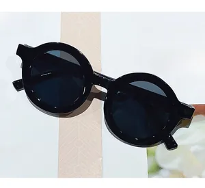 Close-up of black round frame kids sunglasses with dark lenses on a magazine