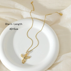 Golden phoenix wing necklace with zircons and green stone detail on white plate