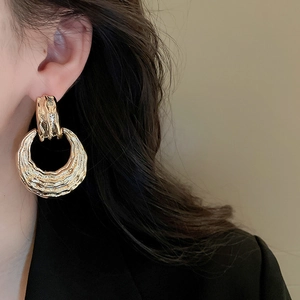 Macro shot of gold textured geometric double hoop earrings on model with metal finish