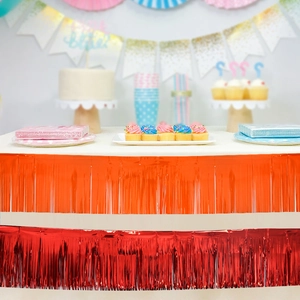 Close-up of double-layer orange and red metallic fringe table skirt for party decor