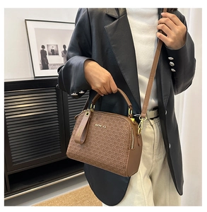 Close-up of brown textured woven leather bag with metal logo and elegant top handle