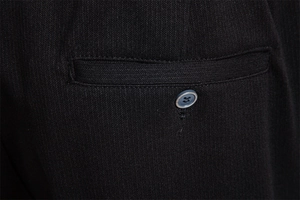 Detail view of black twill business trousers showing the waistband pocket and single button
