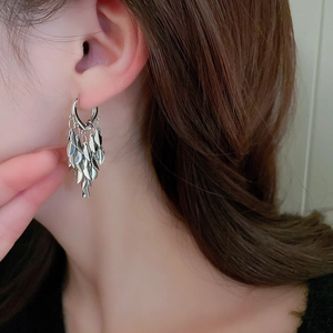 Detailed view of silver leaf tassel earrings worn by a model in a fashion setting