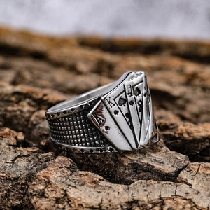 Close-up of vintage stainless steel ring with royal flush poker design on tree bark