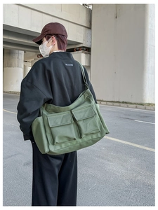 Army green canvas messenger bag detail with flap pockets and wide strap on model