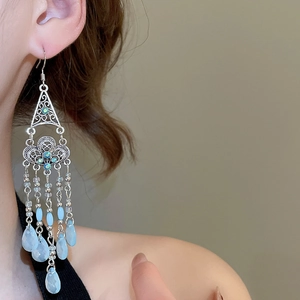 Close-up of ethnic silver-tone earrings with blue beads and long tassels on a model