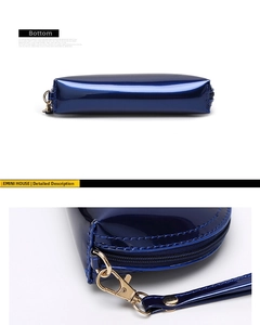 Detail view of glossy navy blue patent leather shell bag with gold zipper and bottom stitch